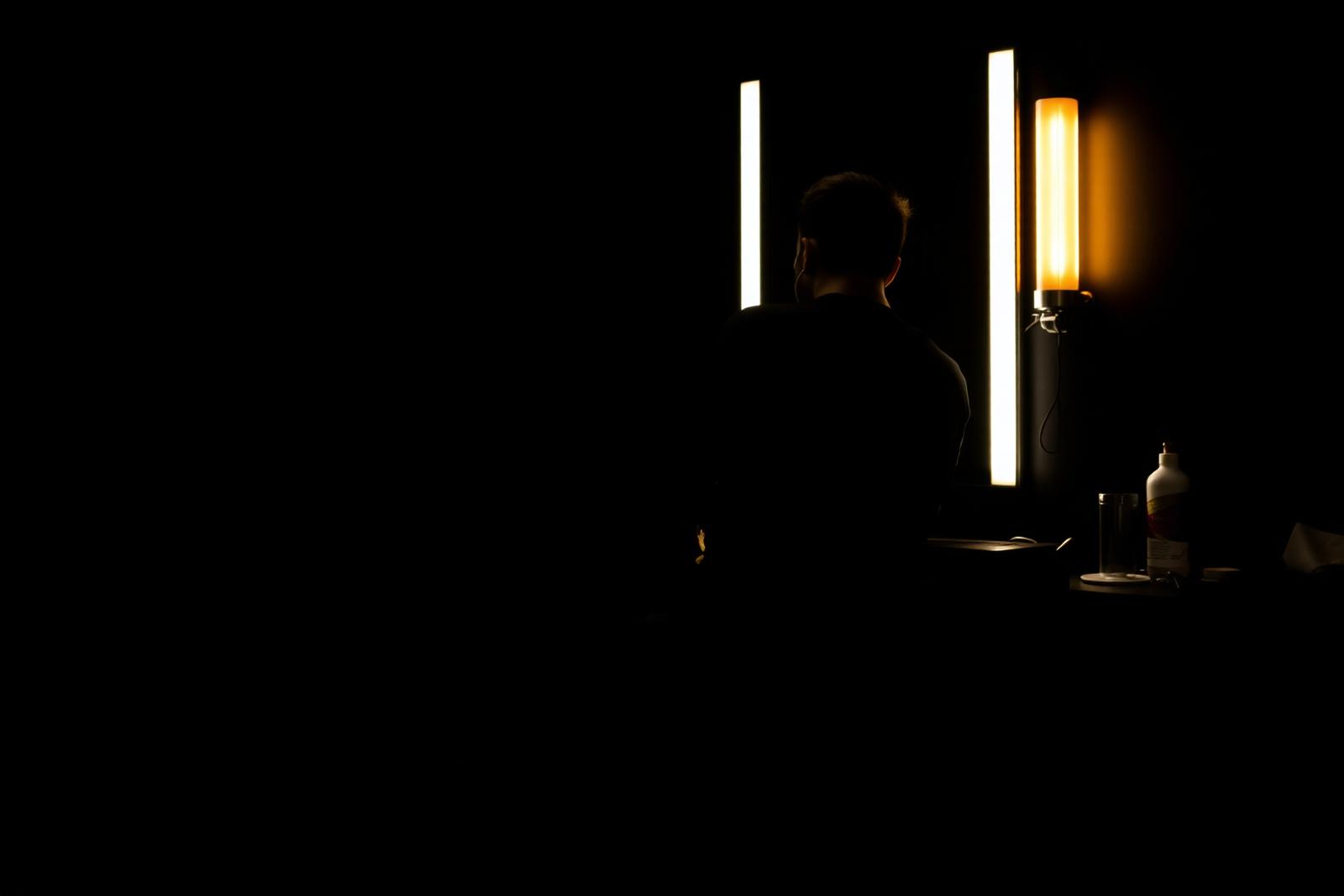 A barber at work beside a lit mirror station